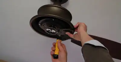 Electrician installing ceiling fan mounting bracket and fixture in Atlanta, GA